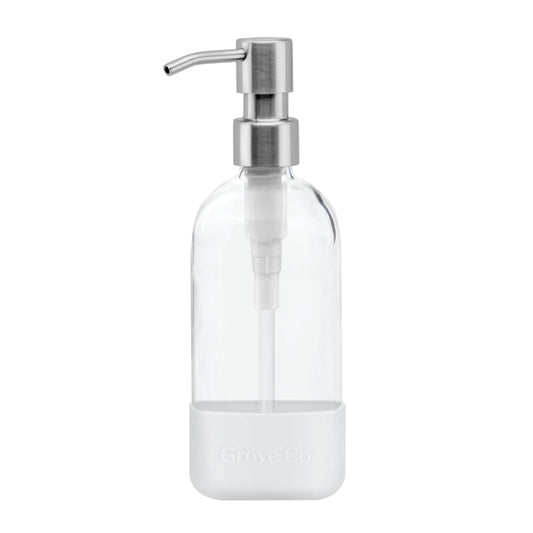 The Refillable Dish Soap Dispenser by Grove Co. features a clear glass body with a stainless steel pump, encased in a white silicone sleeve embossed with Grove Co. Its minimalist design is perfect for eco-friendly homes reducing plastic waste.