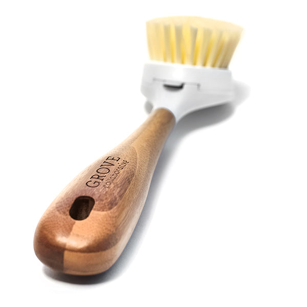 A Grove Co. Replaceable Head Bristle Dish Brush with a bamboo handle engraved with Grove Collaborative, a white plastic head, and light, curved bristles. The wooden-handled brush is isolated on a white background, highlighting its replaceable head design.
