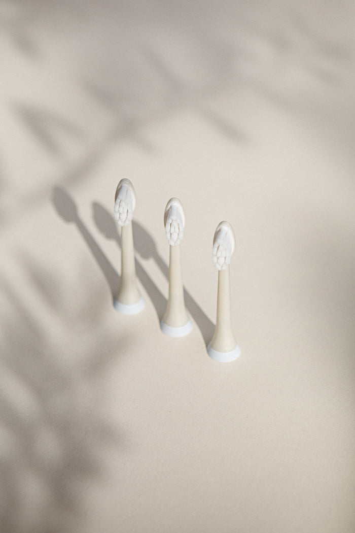 Three Plus Ultra Replacement Toothbrush Heads - Sonicare are lined up on a light beige surface, casting soft shadows. Eco-friendly and designed for Philips Sonicare, they blend sustainability with quality in your oral care routine.