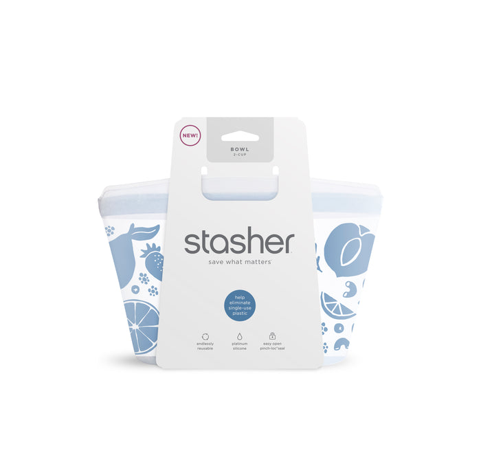 A blue and white reusable 2-Cup Stasher Bowl features fruit illustrations on its packaging. The front label highlights Stasher with food-grade silicone, dishwasher-safe quality, and a NEW! tag. Ideal for use as a to-go container for your meals.