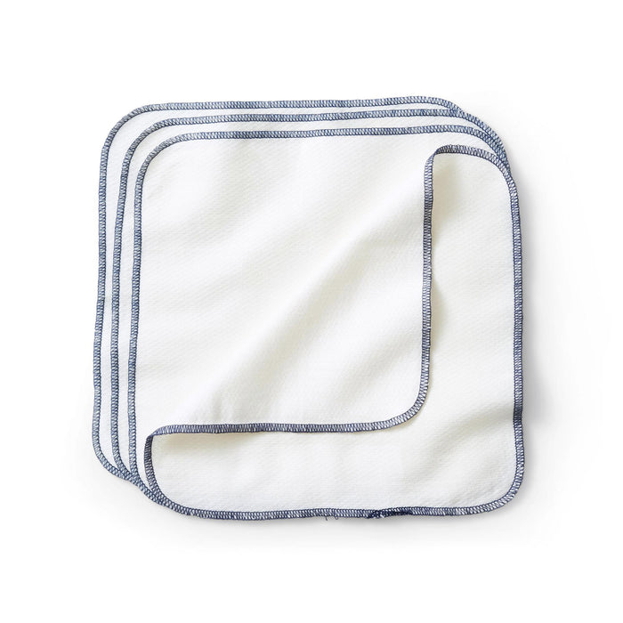Four reusable, white Esembly Baby wipes made of certified unbleached 100% organic cotton are stacked neatly with blue-stitched edges in a slightly overlapping pattern on a plain white surface.