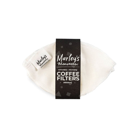 A white, reusable coffee filter made from organic unbleached linen with visible stitching is partially wrapped in black packaging, labeled Marleys Monsters, Reusable Coffee Filters: Basket, promoting a plastic-free coffee experience.