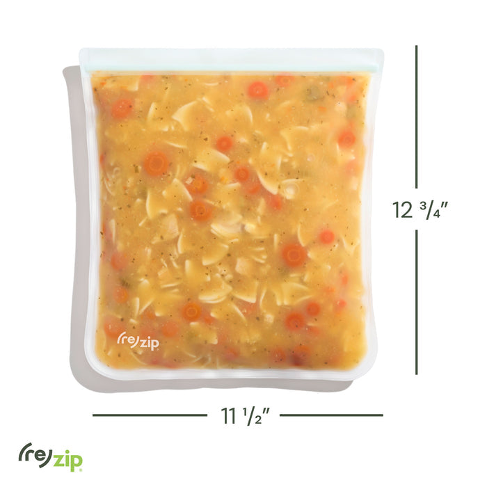 A reusable leakproof gallon bag by (re)zip, measuring 12 3/4" tall by 11 1/2" wide, is shown on a white background filled with chunky soup—noodles, carrots, and broth. Perfect for freezer-safe storage.