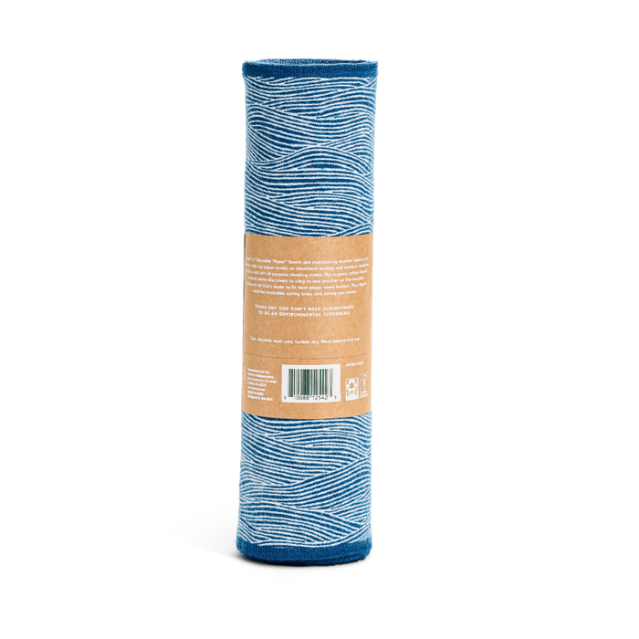 A blue yoga mat with a wavy white design stands upright, wrapped in a brown paper label with text and a barcode, echoing the eco-friendly charm of Grove Co.s Reusable “Paper” Towels.