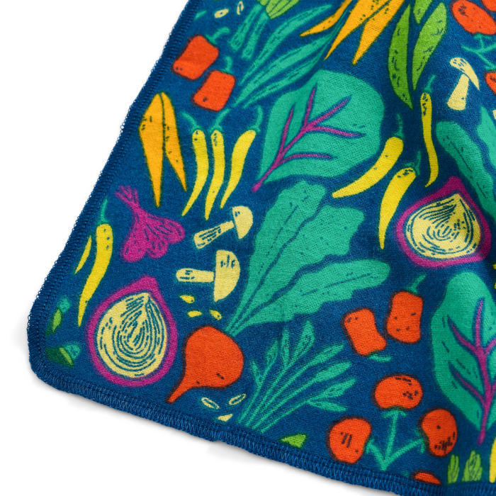 Grove Co.s reusable paper towels, crafted from vibrant organic cotton flannel, showcase carrot, onion, and leafy green illustrations on a blue background. These eco-friendly, machine-washable towels are ideal for those looking for a sustainable paper towel alternative.