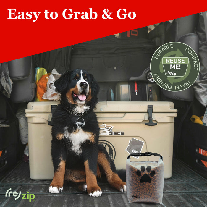 A happy dog sits by a cooler in a car’s back with the (re)zip Reusable Pet Food Storage Bag - Medium, 14 Cup, featuring transparent material and paw prints. Text: Easy to Grab & Go—reusable, durable, and compact.