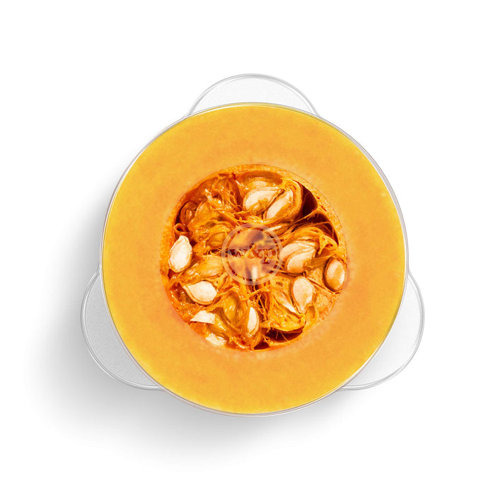 A circular slice of pumpkin, revealing orange flesh and seeds at its center, sits on a round glass dish secured with W&Ps BPA-free Reusable Produce Saver Stretch Lids. The white background highlights freshness and sustainability using these lids.