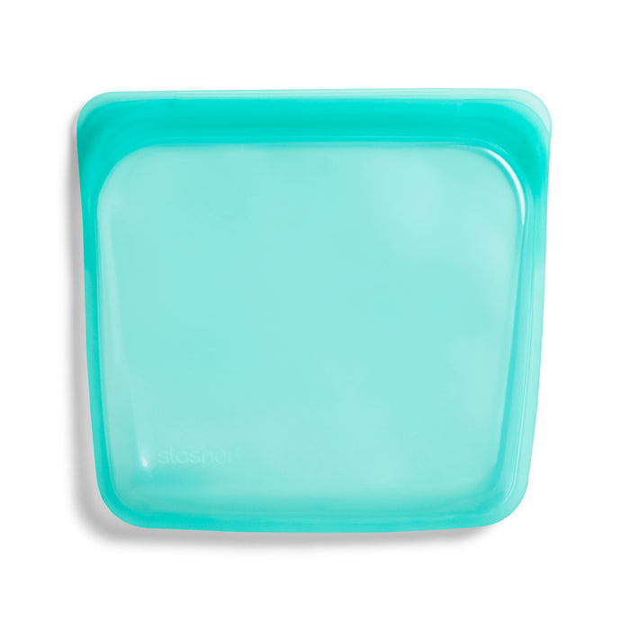 A teal, square-shaped Stasher Reusable Silicone Sandwich Bag is shown against a plain white background. BPA-free and lightweight, its flexible design is ideal for food storage or travel.