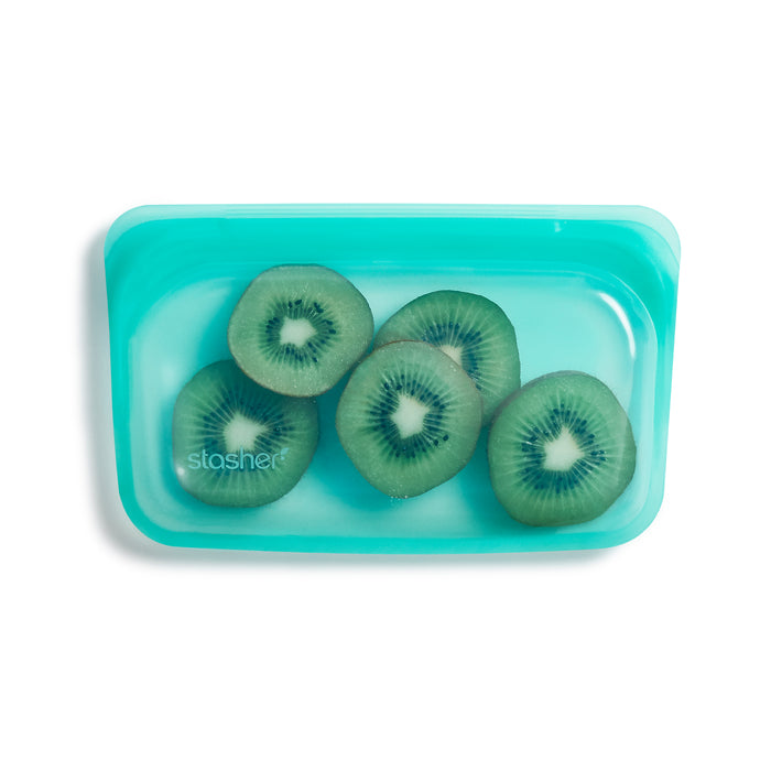 Five slices of kiwi fruit are neatly arranged in a Reusable Silicone Snack Bag by Stasher, featuring premium food-grade silicone and a transparent teal design.