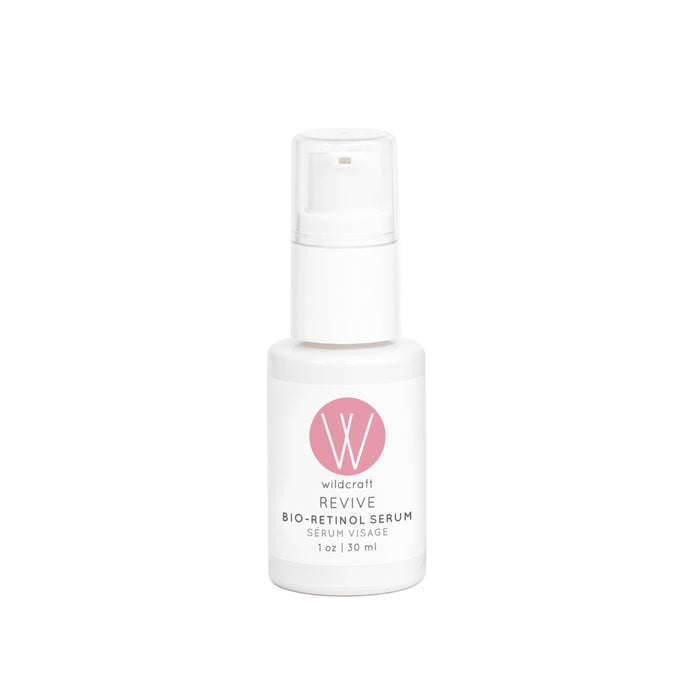 A Wildcraft Revive Bio-Retinol Face Serum white bottle with a pink logo on the front, labeled Serum Visage, 1 oz / 30 ml, promotes its plant-based retinol for skin revitalization. The design includes a transparent cap and pump dispenser.