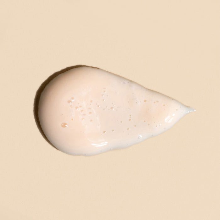 A dollop of Revive Bio-Retinol Face Serum from Wildcraft, a creamy beige liquid, sits on a matching background. Its glossy formula is infused with a plant-based retinol alternative, featuring small air bubbles that enhance texture and promote skin revitalization.