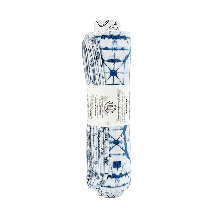 Rolled Unpaper® Towels from Marleys Monsters feature a blue and white shibori-patterned fabric with geometric and star-like designs, ideal for eco-friendly cleaning.