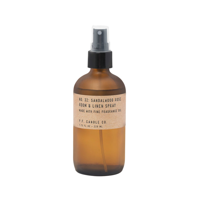 A brown glass spray bottle labeled Room & Linen Spray by P.F. Candle Co. features No. 32: Sandalwood Rose scent, with a woody fragrance. It has a black nozzle and white label with bold black text, offering sophistication for any space.