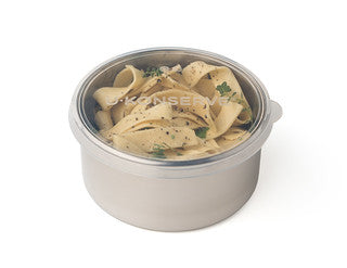The U-Konserve Round Container Large is a stainless steel container with wide, flat pasta garnished with herbs and sealed with a silicone lid for a plastic-free solution.