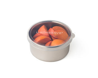 The Round Medium Container from U-Konserve, with its stainless steel build and transparent lid, showcases sliced apricots. This eco-friendly, plastic-free reusable container is perfect for keeping snacks fresh.