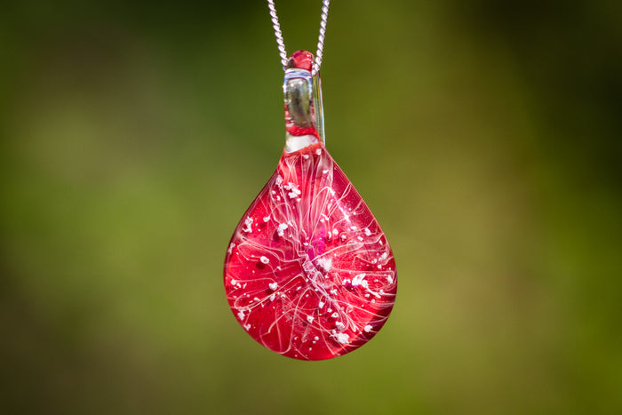 Red ruby slippers inspired glass pendant with white splash pattern on a silver chain, containing cremation ashes.
