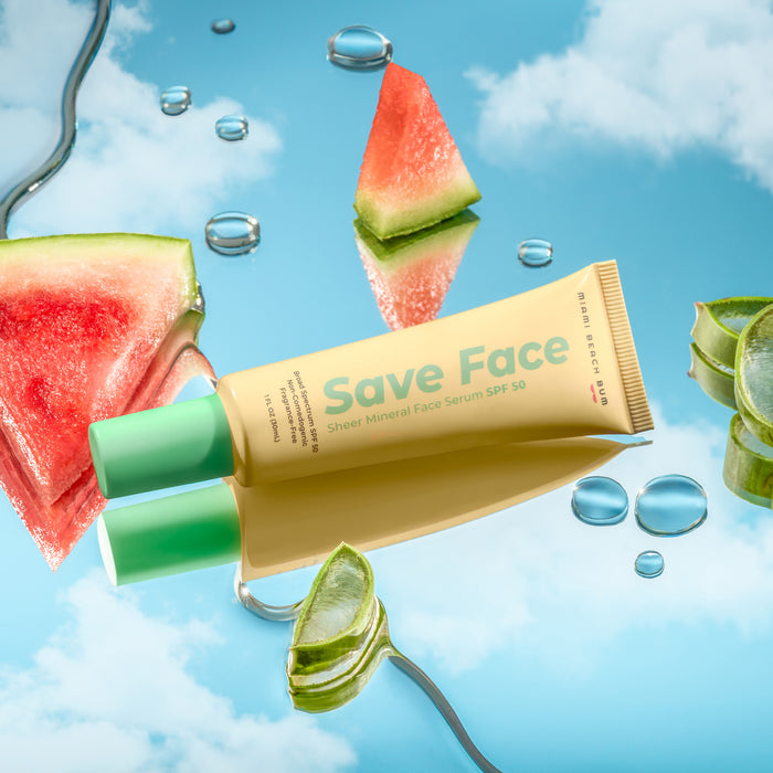 A tube of Miami Beach Bums Save Face Serum - SPF50 is elegantly showcased on a reflective surface with watermelon slices, aloe pieces, and water droplets against a blue-toned background. This non-comedogenic formula is also Hawaii Reef-Friendly.