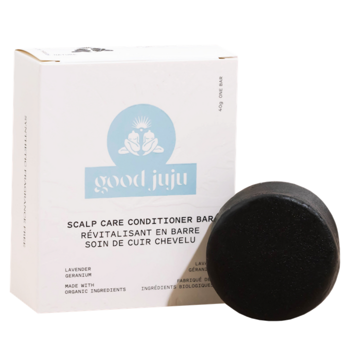 A round, black Scalp Care Conditioner Bar from Good Juju Body & Home is shown in front of a white box labeled with its name and ingredients—lavender and geranium—in both English and French.