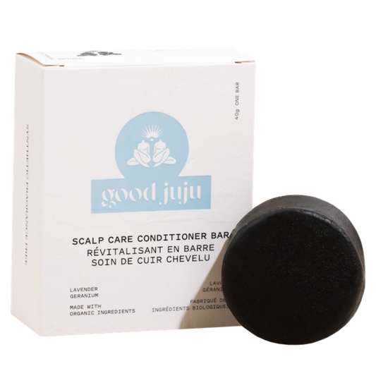 A round, black Scalp Care Conditioner Bar from Good Juju Body & Home is shown in front of a white box labeled with its name and ingredients—lavender and geranium—in both English and French.