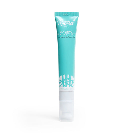 The Rooted Beauty Sensitive Skin Daily Moisturizer comes in a turquoise tube with a white cap, featuring aloe and chamomile for delicate skin. It has a leaf pattern at the bottom, is non-greasy, and proudly EWG VERIFIED™ for peace of mind.