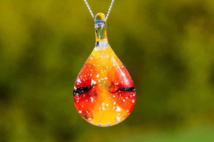 Teardrop glass pendant in setting sun colors with cremation ashes on a chain