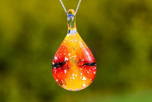 Teardrop glass pendant in setting sun colors with cremation ashes on a chain