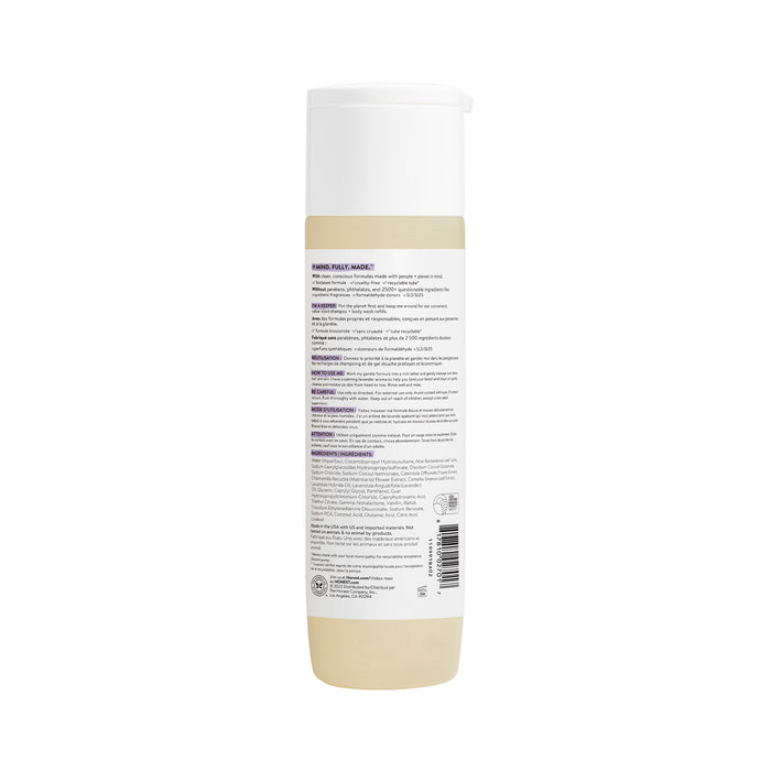 The image shows the back of a cylindrical bottle with a white cap, featuring product details in multiple languages. It highlights its tear-free formula with Aloe + Chamomile Extract, includes a barcode and symbols, and indicates it is The Honest Companys Shampoo + Body Wash.
