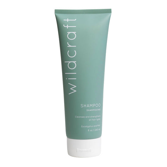 A green tube of Wildcraft Shampoo displays white text reading SHAMPOO and Cleanses and strengthens all hair types. Enriched with quinoa protein, this 8 oz (240 ml) Eucalyptus and Mint shampoo rejuvenates all hair types.