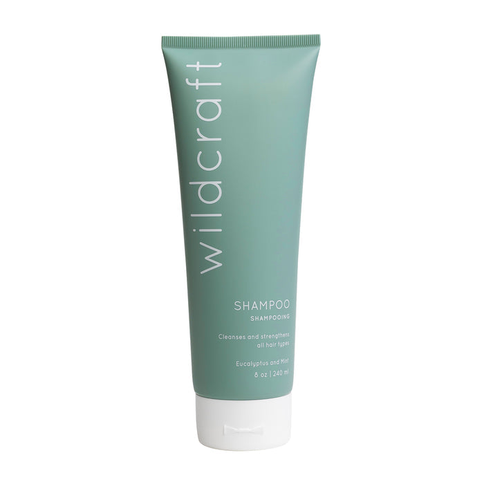 A green tube of Wildcraft Shampoo stands upright, its label reading: Wildcraft Shampoo, cleanses and strengthens all hair types with quinoa protein, 8 oz / 240 ml.
