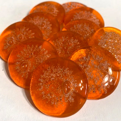 Orange glass sharing stones infused with cremation ash, glossy round cabochons shown together.