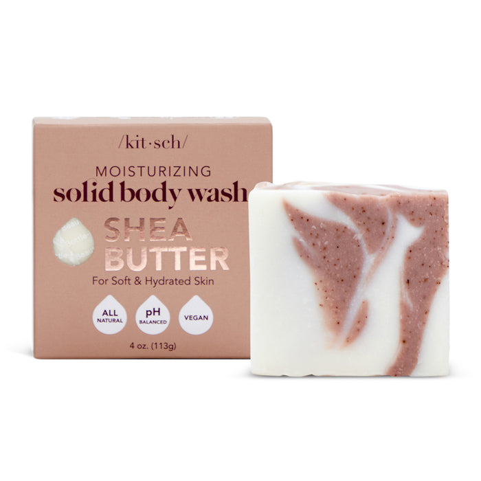 The Kitsch Shea Butter Moisturizing Solid Body Wash stands before its beige packaging, featuring a super-hydrating, all-natural, pH-balanced, vegan formula. The white bar includes brown specks of plant-derived exfoliants to gently moisturize your skin.