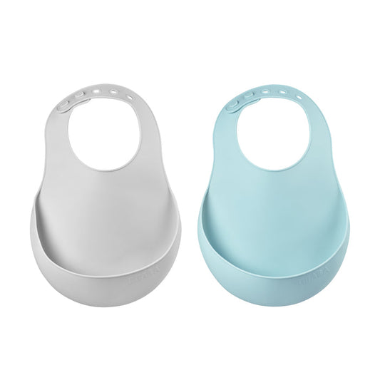 Displayed side by side are two BEABA Silicone Bibs, a must-have for feeding. In light gray and light blue, they feature snap closures and large front pockets to catch spills. Dishwasher safe for easy cleaning.