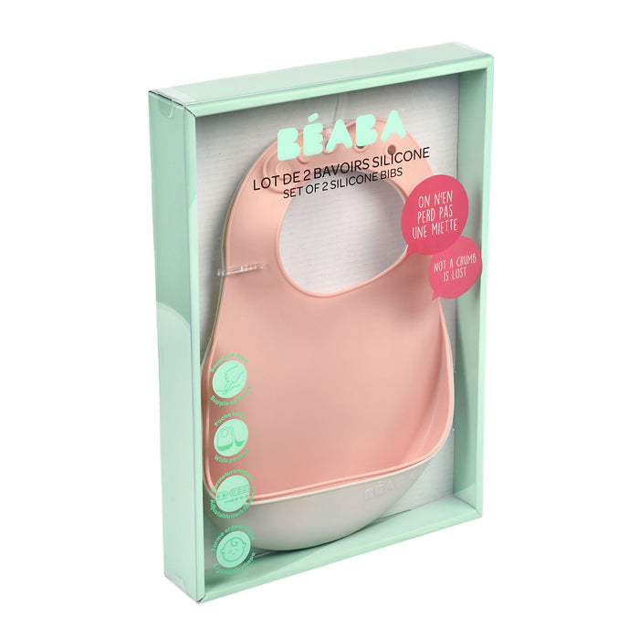 The BEABA Silicone Bibs set includes a pink and white bib, essential for feeding. The light green packaging features illustrations of its easy-clean design and adjustable neck. French text details the product, which is dishwasher safe for convenience.