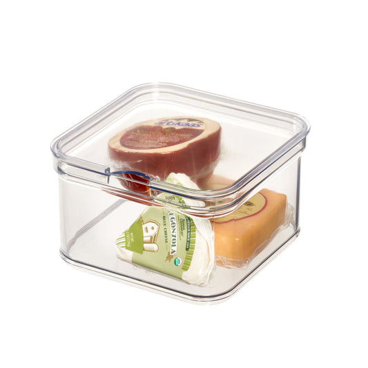 The iDesign Single Fridge Bin, made with recycled plastic, is a durable, transparent square container that holds packaged cheese: one wheel with a red rind and label, another in orange wax, and a rectangular block in white wrapping. This BPA-free bin keeps your cheeses fresh.