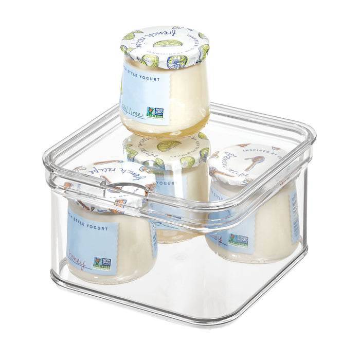 Four jars of yogurt with decorative labels are arranged in iDesigns Single Fridge Bin made from recycled plastic. One jar is upside down. The clear container with rounded edges and a snug-fitting lid keeps your refrigerator neatly organized.