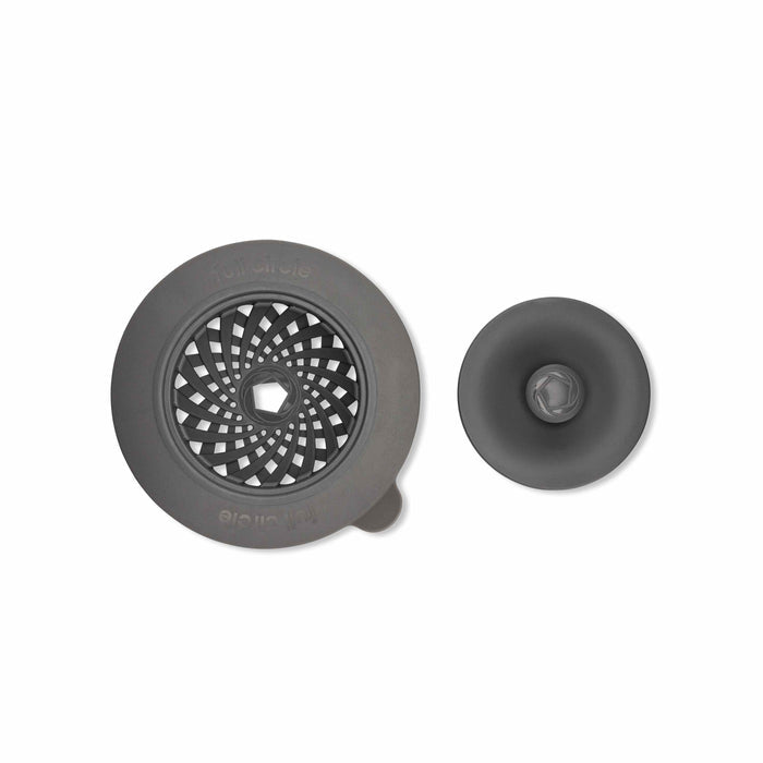 Introducing the Full Circle Sinksational Sink Strainer duo, crafted from eco-friendly materials. The large strainer features a grid with a central hole, and the smaller has a simple design with a knob. Both offer sustainable functionality in gray on a pristine white background.