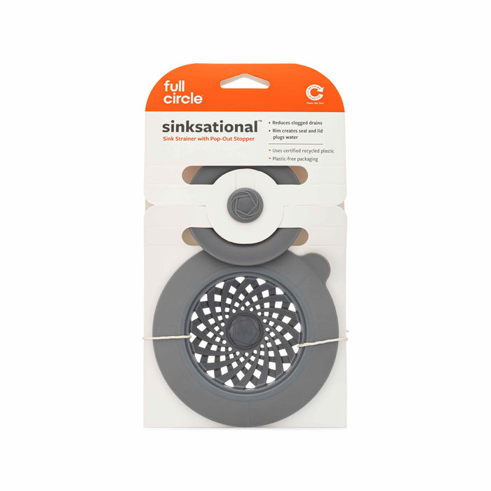 The Full Circle Sinksational Sink Strainer in gray, featuring a recycled plastic strainer and pop-out stopper, is packaged to highlight its user-friendly design and eco-friendly materials for preventing clogged drains.