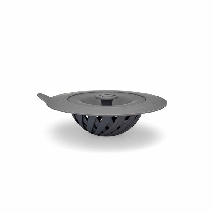 The Full Circle Sinksational Sink Strainer, a dark gray silicone kitchen tool with a flat lid and side handle, is crafted from eco-friendly materials. This recycled plastic basket-design strainer is perfect for anyone seeking sustainable choices and is showcased on a plain white background.
