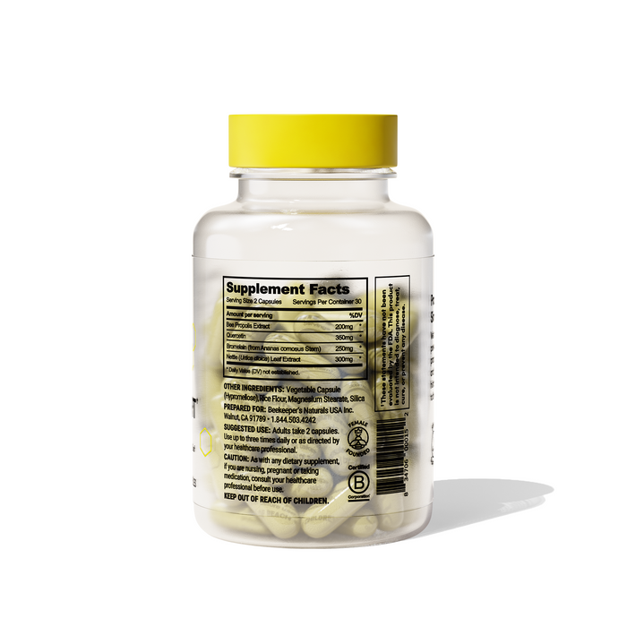 A transparent bottle with a yellow lid, labeled Sinus Support by Beekeepers Naturals for immune support, contains capsules. The supplement facts label details ingredients and nutritional info while its shadow elegantly drapes across the white background.