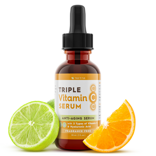 A bottle of Tree To Tubs Skin Brightening Triple Action Vitamin C Serum for Face, with a black dropper cap, is centered. The anti-aging formula includes three types of Vitamin C and hyaluronic acid. Fragrance-free, it’s portrayed with a lime wedge and an orange slice nearby.