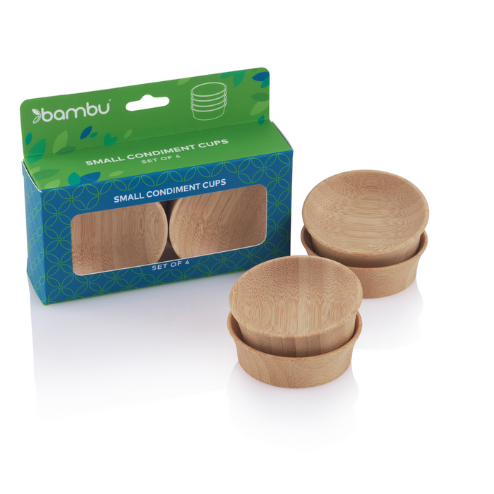 A set of four USDA Certified Biobased small organic bamboo condiment cups stands next to an open green and blue box with circular patterns. The text says bambu and Small Condiment Cups, showcasing eco-friendly dining elegance with two stacks of these cups.