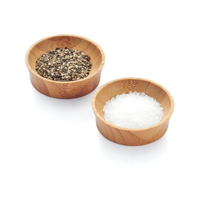 Two Bambu Small Condiment Cups sit on a white background; the left cup contains coarse black pepper, and the right is filled with coarse sea salt.