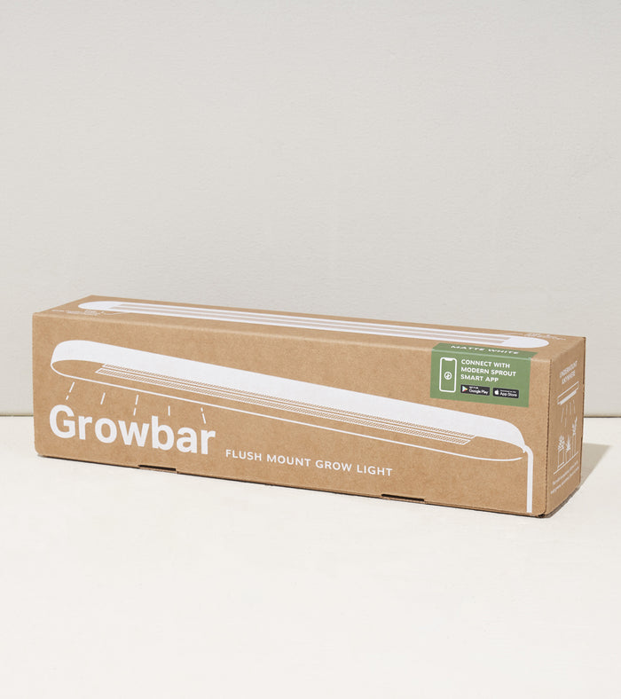 The Smart Growbar by Modern Sprout features a simple illustration on its cardboard box and highlights its compatibility with a smart grow app. It provides full-spectrum LED support for houseplants, set against a neutral-colored background.