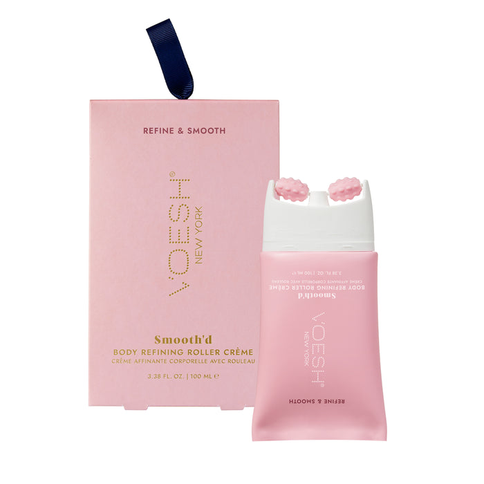 The VOESH New York Smoothd Body Refining Roller Creme, aimed at crepey skin, comes in a pink bottle with a textured roller applicator. Its packaging is a matching pink box embellished with gold text and a blue ribbon tab.