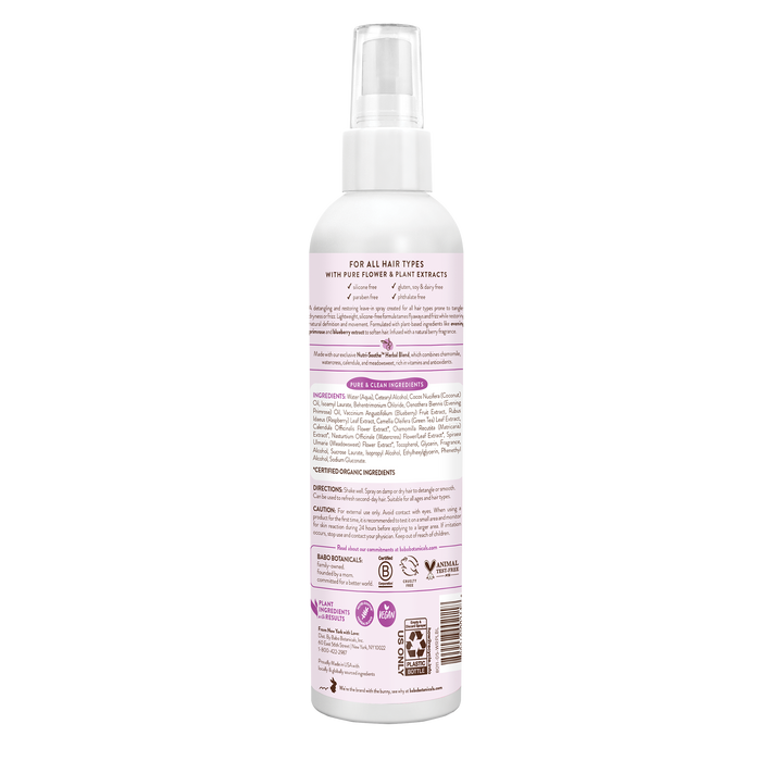 The Babo Botanicals Smoothing Conditioning Spray features a pink label with text and a white-capped spray bottle. Its silicone-free, suitable for all hair types, lists ingredients, and combats frizz with certifications and icons at the bottom.