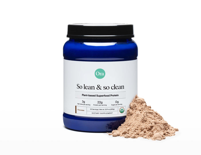 A blue Ora Organic container of So Lean & So Clean: Daily Active Plant Protein with essential amino acids is shown. It includes nutritional information, and a pile of chocolate-flavored powder lies next to it.