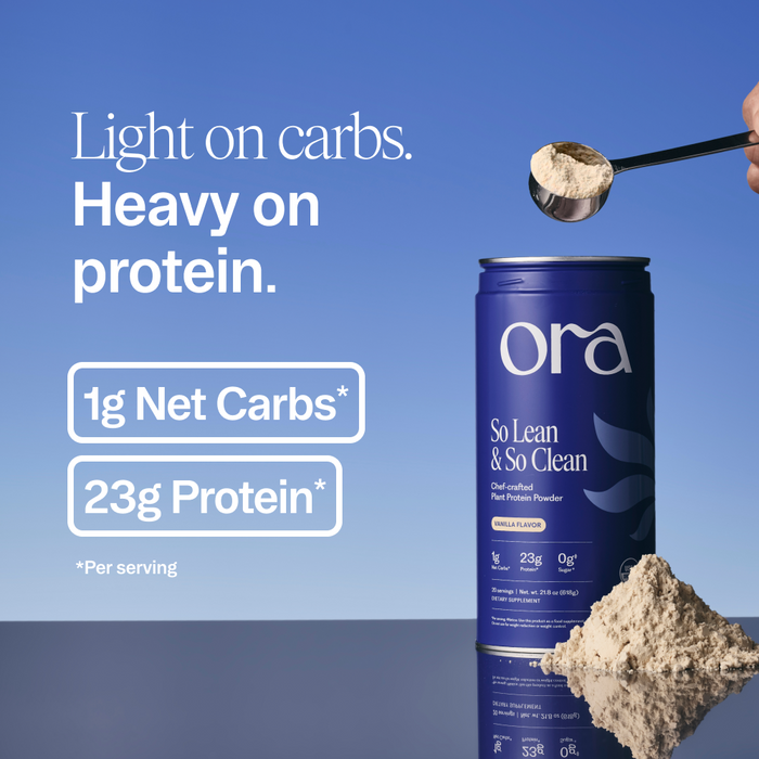 A container of Ora Organic So Lean & So Clean: Daily Active Plant Protein Powder sits on a surface with a scoop above it. Text highlights: Light on carbs. Heavy on protein. 1g net carbs*, 23g plant protein* per serving.