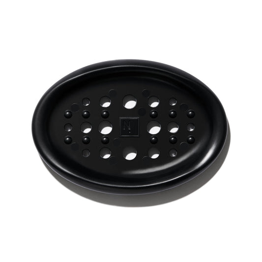 The NOT!CE Hair Co Bar Dish is a black, oval silicone plate with circular drainage holes and a textured N logo, perfect for plastic-free hair care enthusiasts.
