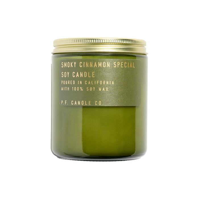 A green candle jar with a gold lid features a label reading Smoky Cinnamon Special Soy Candle from P.F. Candle Co. This fresh, earthy scent is poured in California using 100% soy wax, resembling their standard candles line.
