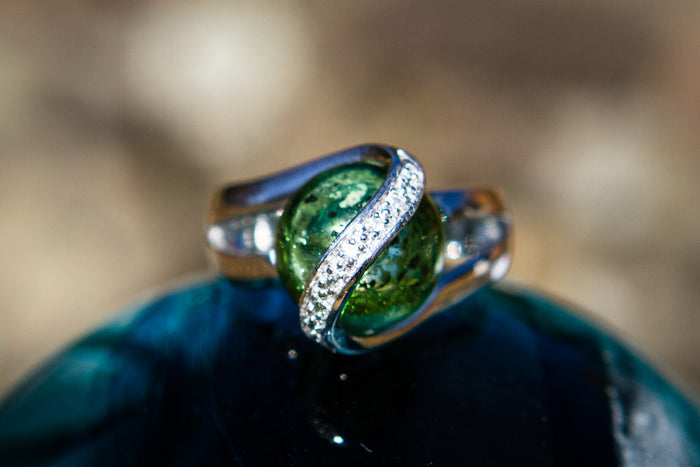 Sterling silver ring lined with zircons and a 12mm green glass marble infused with cremation ash in a curved pavé band